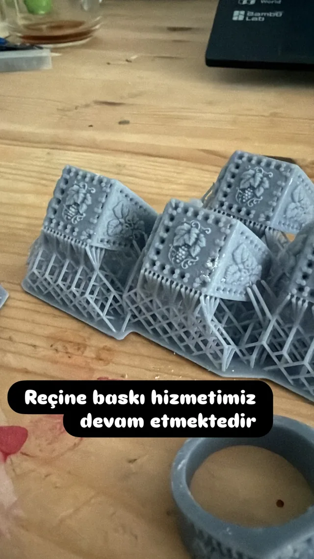 Atölye masasında destek yapıları henüz çıkarılmamış, desenli gri reçine baskı parçaları